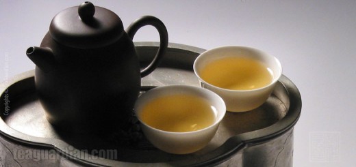 A small Yixing teapot with two porcelain gongfu teacups on a pew